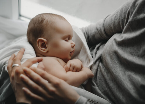 Charming newborn boy sleeps on mother's arms