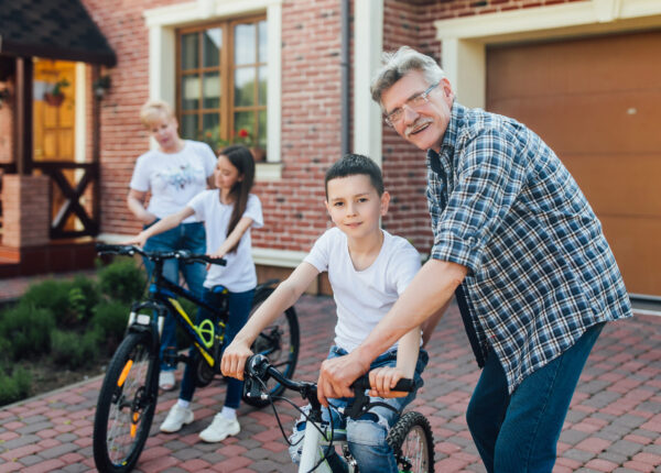 Help,generation, safety and people concept - happy grandfather and boy with bicycle and bike teach together.