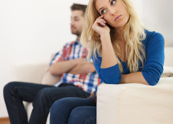 Crying woman sitting with her boyfriend in the background
