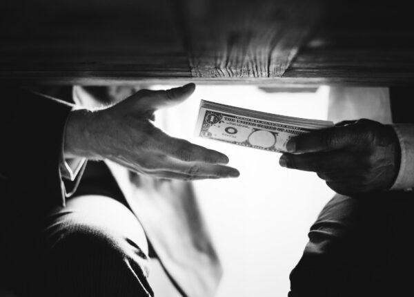 Hands passing money under the table corruption and bribery